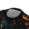 A close-up view of a black t-shirt with a Halloween-themed print, featuring jack-o'-lanterns, spooky trees, and falling leaves.