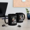 Black ceramic mug with a graphic of a cow wearing glasses and holding grass, with text.