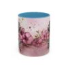 Ceramic mug with pink watercolor floral design and text 'Just A Mom Who Loves Red Delicious Apples'.