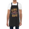Black apron with 'King of the BBQ' text and grilled ribs graphic, perfect for grilling enthusiasts.