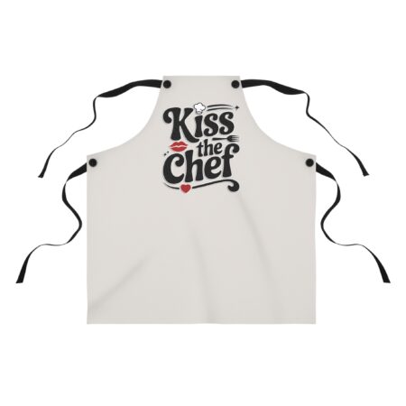 Cream kitchen apron with 'Kiss the Chef' graphic, featuring red lips, chef hat, fork, and heart accent. Perfect for cooking.