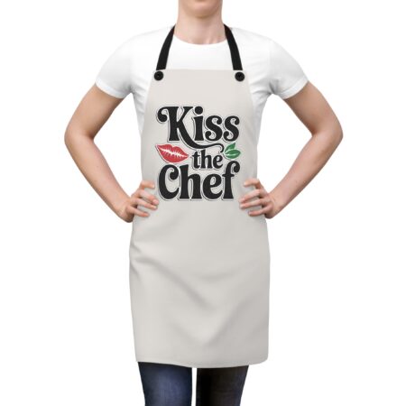 Light gray kitchen apron with 'Kiss the Chef' text, red lips, and green leaves graphic.