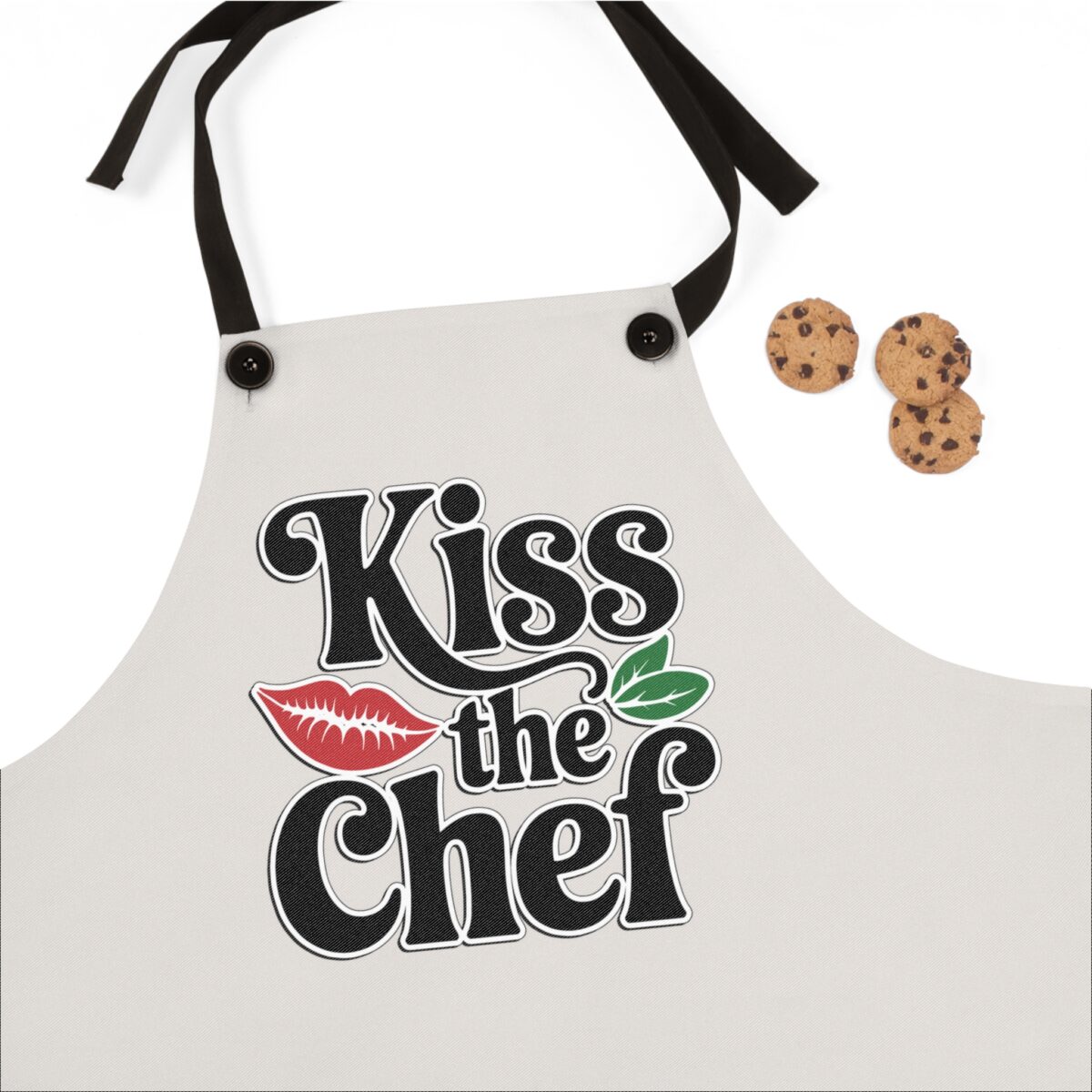 Chef apron with 'Kiss the Chef' text, red lips graphic, and green leaves. Perfect kitchen wear for culinary enthusiasts.
