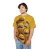 A man wearing a yellow t-shirt featuring a chaotic, melting smiley face design with exaggerated smiles and dripping texture.
