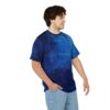 Man wearing a blue t-shirt with an abstract paint stroke design and light-wash jeans.