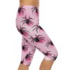 A person wears pink capri leggings featuring an all-over black spider and subtle web pattern, isolated on a white background.