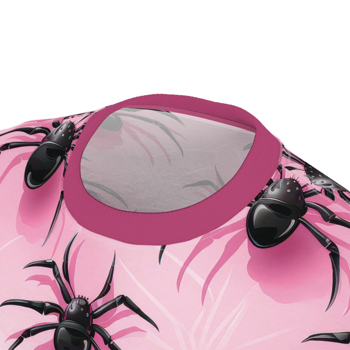 A t-shirt featuring a vibrant pink background with a repeating graphic of black, glossy spiders and abstract floral elements. The neckline is accented with a contrasting pink trim.