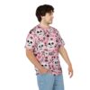Pink background with scattered skulls, roses, and floral elements in black and white, covering this 3D graphic t-shirt.