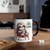 A white ceramic mug with a black handle, featuring a cartoon sloth holding a coffee cup that says "first coffee".