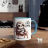 A white ceramic mug with a blue rim and handle, featuring a cartoon sloth sitting in a chair holding a tiny coffee cup.
