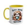 White ceramic mug with yellow handle and interior. Features a fluffy sloth holding a polka-dot mug.