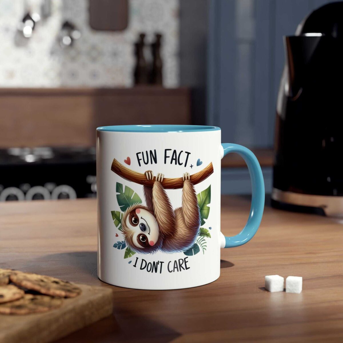 White ceramic mug with a light blue handle and rim, featuring a cartoon sloth hanging from a branch with leaves, and text.