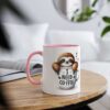 White ceramic mug with pink handle and rim, featuring a cartoon sloth saying "I need coffee".