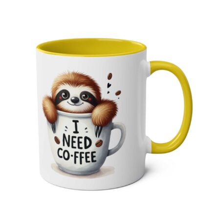 White ceramic mug with yellow handle and interior, featuring a cute sloth peeking out of a coffee cup that says "I need coffee."