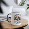 White ceramic coffee mug with a navy blue rim and handle, featuring a cute sloth illustration and the words "Natural Born Chiller".