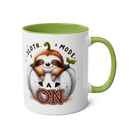 White ceramic mug with a green handle and interior, featuring a cute sloth in a pumpkin with "Sloth Mode On" text.