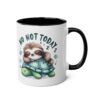 A white ceramic mug with a black interior and handle, featuring a cartoon sloth asleep on a turtle.