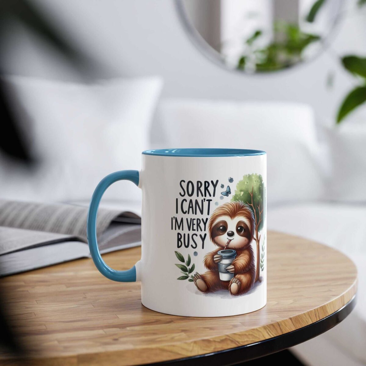 White ceramic mug with blue interior and handle, featuring a cartoon sloth holding a coffee cup and text.
