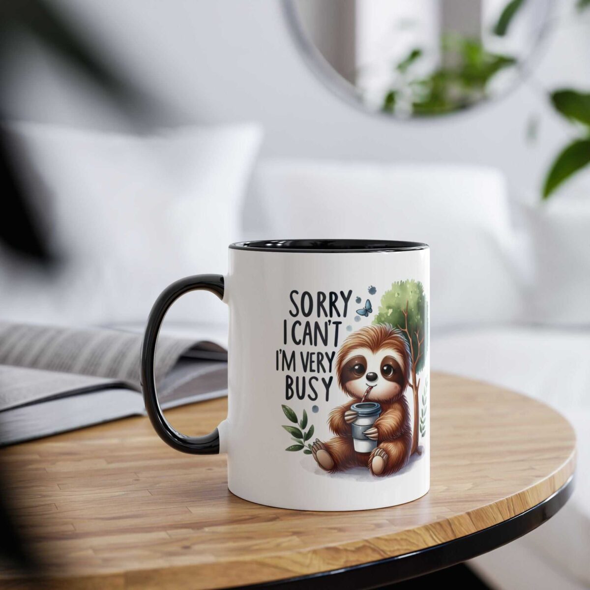White ceramic mug with black handle and rim, featuring a cartoon sloth drinking from a cup and the text 'Sorry I can't I'm very busy'.