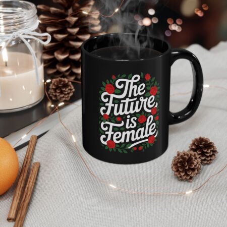 Black ceramic mug featuring white "The Future Is Female" text surrounded by a red rose and green leaf wreath.