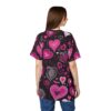 Rear view of a woman wearing a black t-shirt with a repeating pattern of pink and white hearts and other decorative elements.