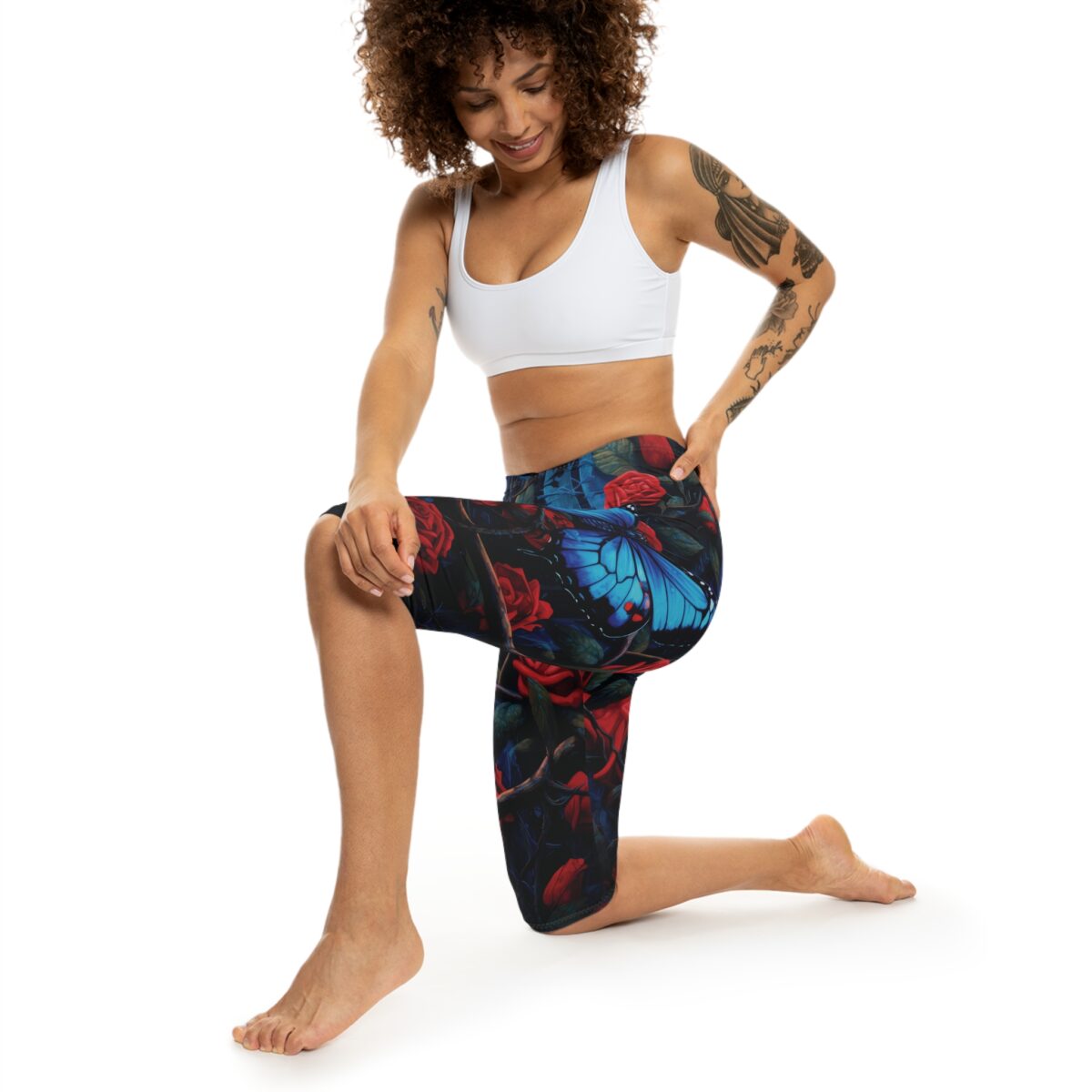Capri leggings featuring a dark, floral print with vibrant blue butterflies and red roses.