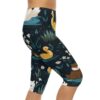 Capri leggings featuring a dark navy background with a whimsical print of swans, ducks, cats, and otters in a pond with small white flowers.