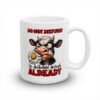 White ceramic mug with a cartoon cow eating a daisy, text reads