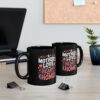 A black mug displays text that reads 'A Mother's Love Is The Heart Of A Home' in pink and white lettering with heart accents.