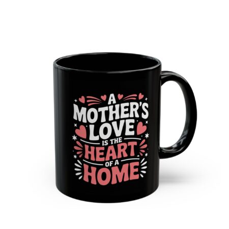 This black mug features the heartwarming quote 'A Mother's Love Is The Heart Of A Home' in stylized white and pink lettering with small heart and star accents.
