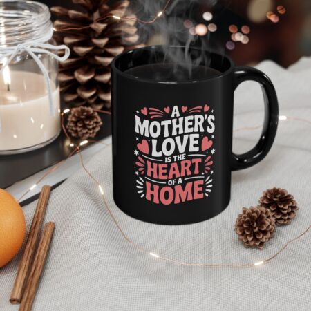 A black mug features pink and white text reading 'A Mother's Love Is The Heart Of A Home', adorned with hearts and stars.
