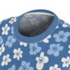 White and light blue floral shapes with dark blue centers cover this seamless pattern tee, set against a textured blue background.