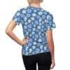 White and light blue flowers with dark blue centers cover this seamless pattern tee shirt, set against a vibrant blue background.