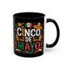 Fiesta-themed graphics, including a Mexican flag, sombrero, maracas, and festive text 'CINCO DE MAYO', decorate this black mug.