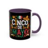 A black mug with a purple handle and interior features the words CINCO DE MAYO in colorful text surrounded by Mexican cultural icons like sombreros, maracas, and bottles.