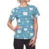 White cartoon cat faces and small white daisies cover this all over print apparel with blue horizontal stripes and thin yellow accent lines.