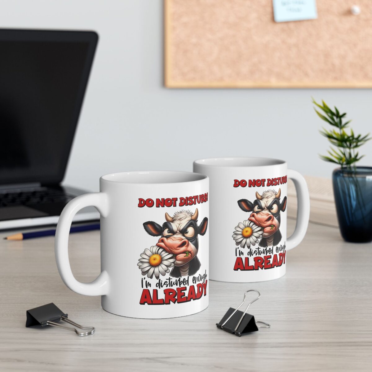 A grumpy cow with a daisy in its mouth reads "DO NOT DISTURB" and "I'm disturbed enough ALREADY" on a white mug.