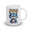 A grumpy blue cat with yellow eyes sits on a white mug, with the text 
