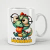 White ceramic mug with a cartoon dinosaur wearing glasses and sticking its tongue out, with text that reads 