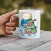 White ceramic mug with a festive holiday design featuring a Christmas tree, snowman, hot cocoa, and snowflakes.
