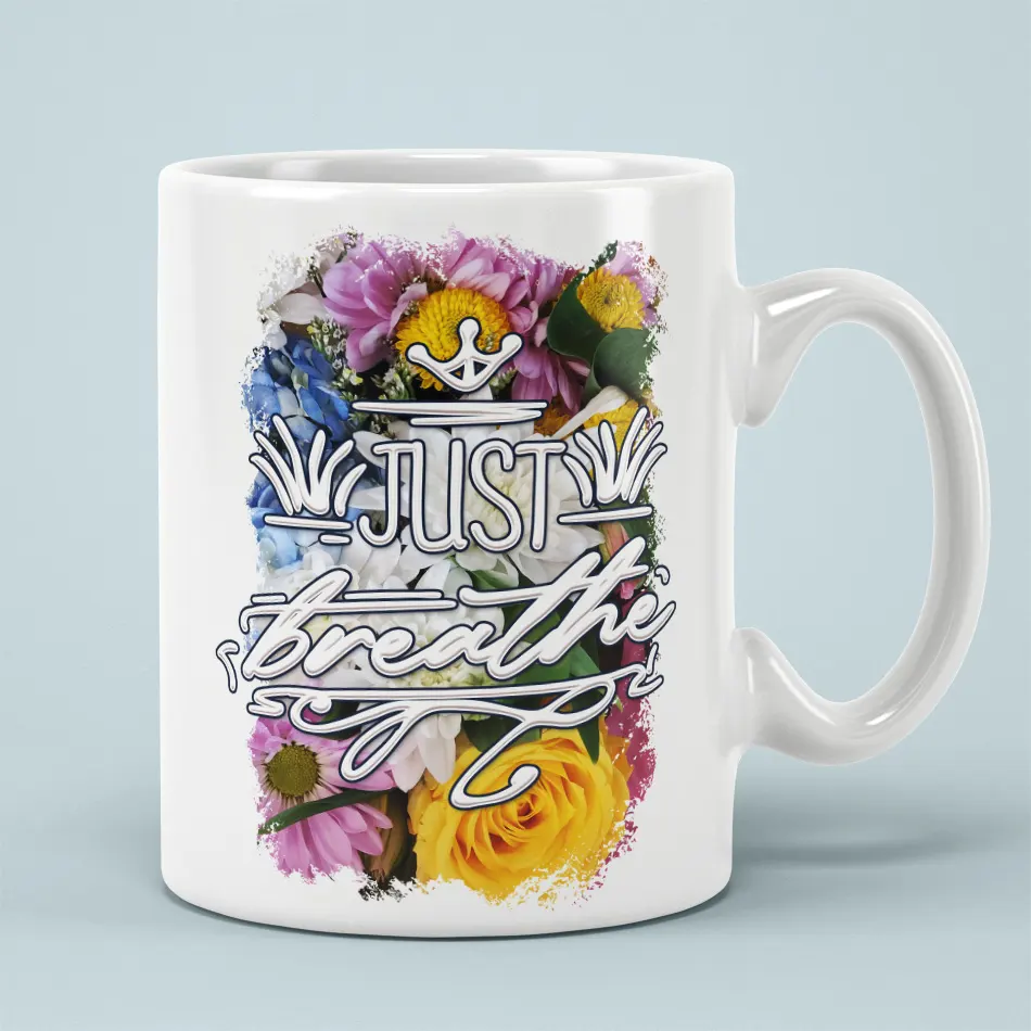 White ceramic mug with a vibrant floral design and the text "JUST breathe" in a decorative font.