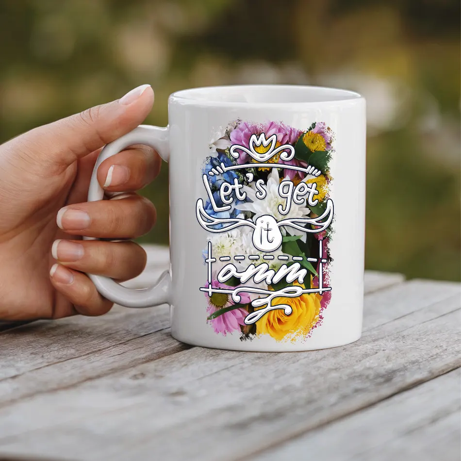 White mug with floral accents and "Let's Get It Omm" text.