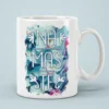 White coffee mug with 'Namaste' in blue text against a vibrant floral background of teal, pink, and white orchids.