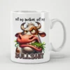 A white ceramic mug with a cartoon cow with a sassy expression eating grass.