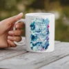 White ceramic mug with a floral design and text that reads 