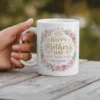 White ceramic mug with a floral wreath design saying 