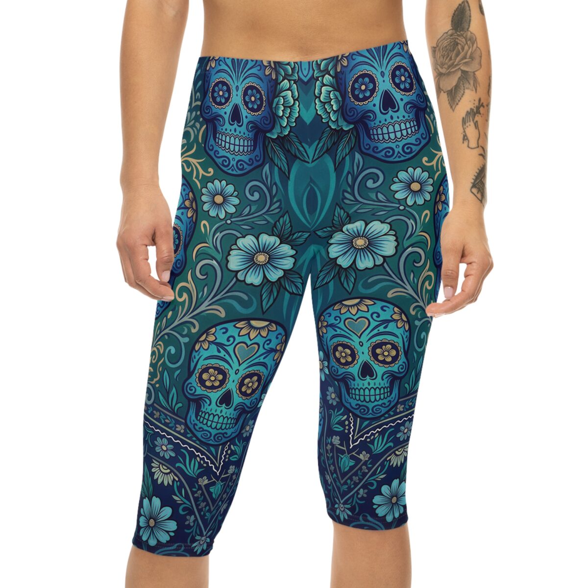 Blue Sugar Skull Capri Leggings featuring a Day of the Dead floral yoga pattern. The form-fitting capri leggings display intricate teal and dark blue sugar skulls, light blue flowers, and swirling botanical motifs on a smooth, snug fabric.