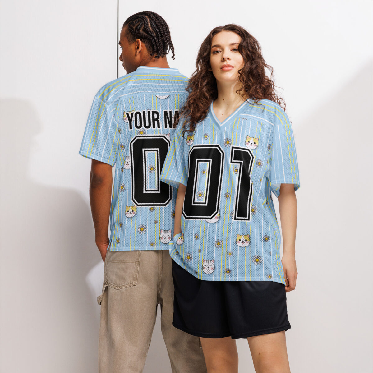 Light blue jersey with thin yellow stripes, white pinstripes, and a repeating pattern of cute cat faces and small white flowers.