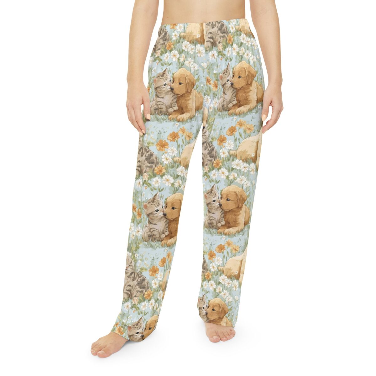 Pajama pants featuring a seamless all over print of cute kittens and golden retriever puppies nestled among wildflowers on a light blue background.