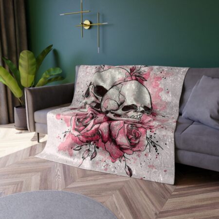 Plush throw blanket featuring a detailed graphic of two skulls intertwined with pink roses and splattered pink ink.